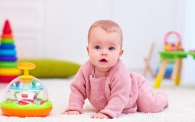 cute little baby girl crawling on the carpet among the development toys